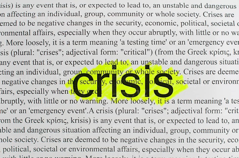 Typed text Crisis on white paper.Yellow marked