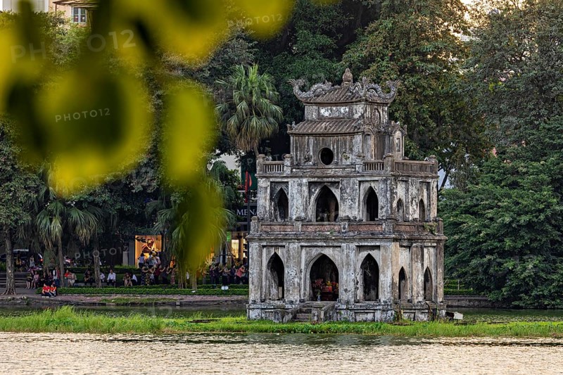 Old tower on the shore of a green park landscape, illuminated by evening light, The Turtle Tower in Hoan Kiem Lake in the old town of Hanoi Vietnam