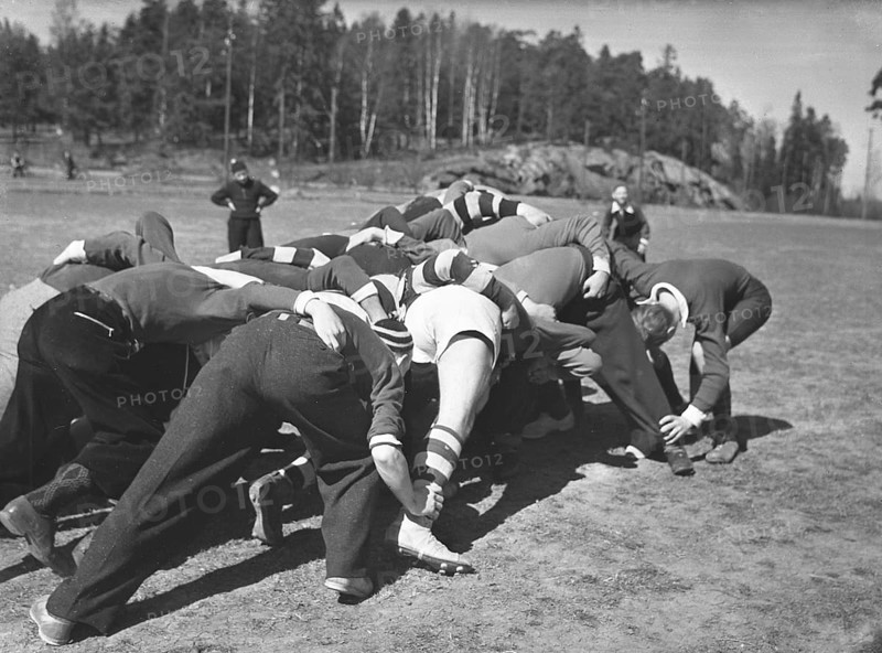 1940s rugby. A group of rugby players are practising on a sunny spring day. The focus is on the ball and all players try their best to get their hands on it. Sweden May 2 1940. Kristoffersson ref 128-12