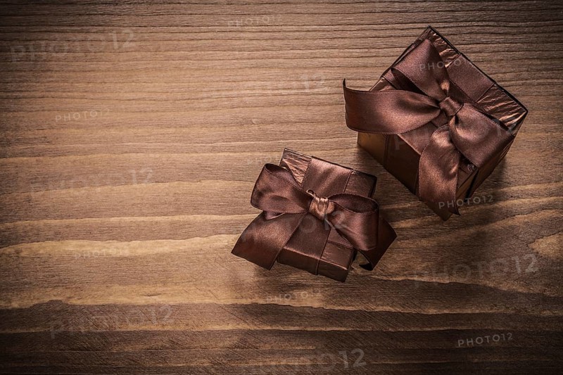 Packed glittery gift containers with ribbons on vintage wooden board