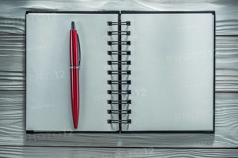 Opened notebook pen on white wooden board