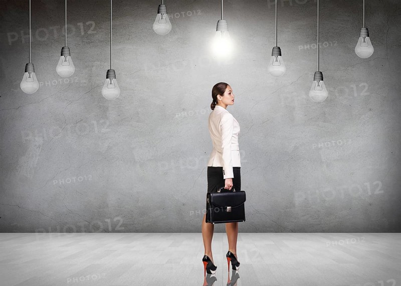 Business woman stands in a gray room with hanging bulbs