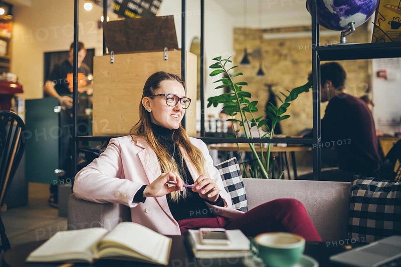 Dreaming pretty lady thinking of ideas sitting in cafe, creative profession. theme modern female blogger. young woman with pen in hand thinking on plans, recreation time in stylish coworking space