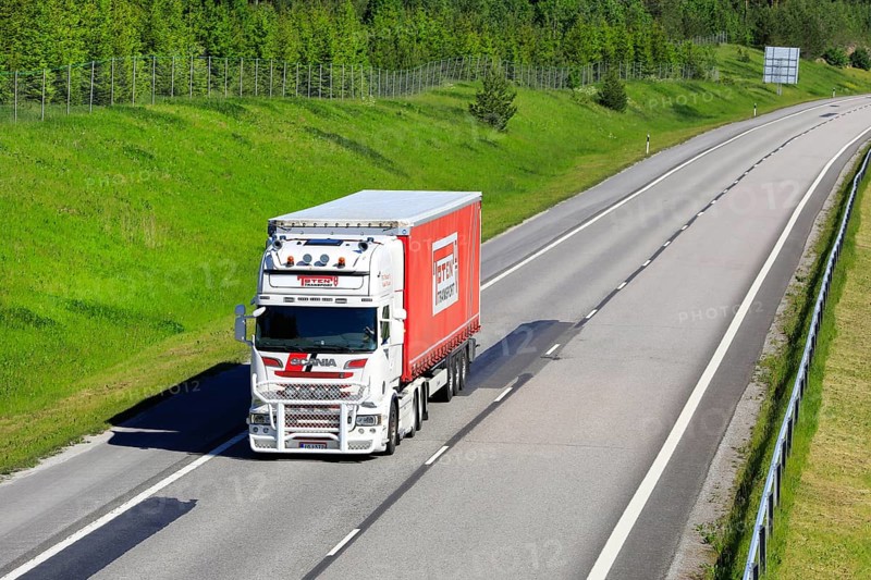 White and red Scania R560 semi trailer truck Toten Transport Oy transports goods along motorway with slow traffic. Salo, Finland. June 12, 2020