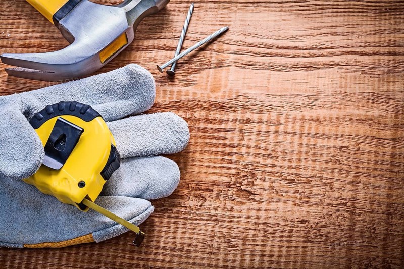 Yellow roulette in protective glove hammer nails on vintage wooden board construction concept