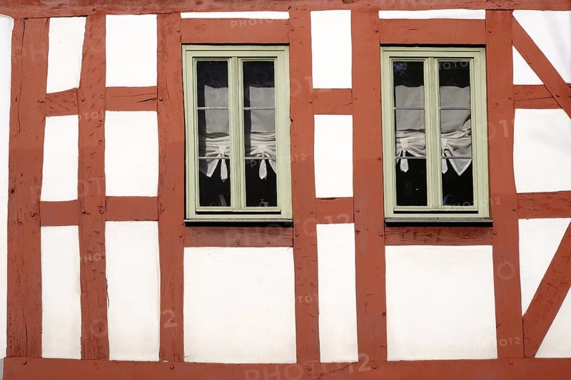 The beam construction and timber frame of a half-timbered house with two narrow wooden windows