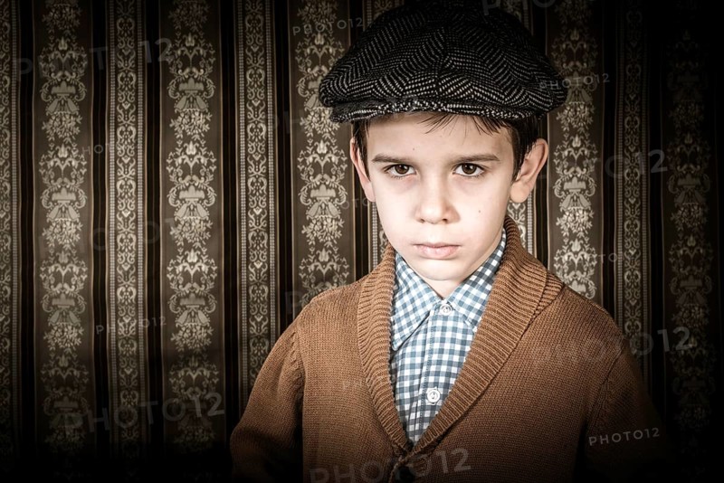Frowning child in vintage clothes and hat. Close up shot