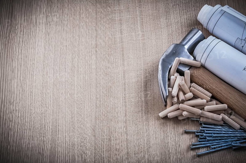Blueprints hammer dowels nails on wooden board construction concept