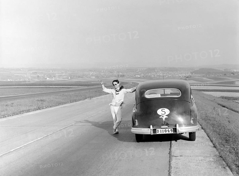 Vaction in Italy in the 1951. A man at his car during a car vacation trip in Italy. He has stopped along a road and waves at the photographer. Conard ref 1666