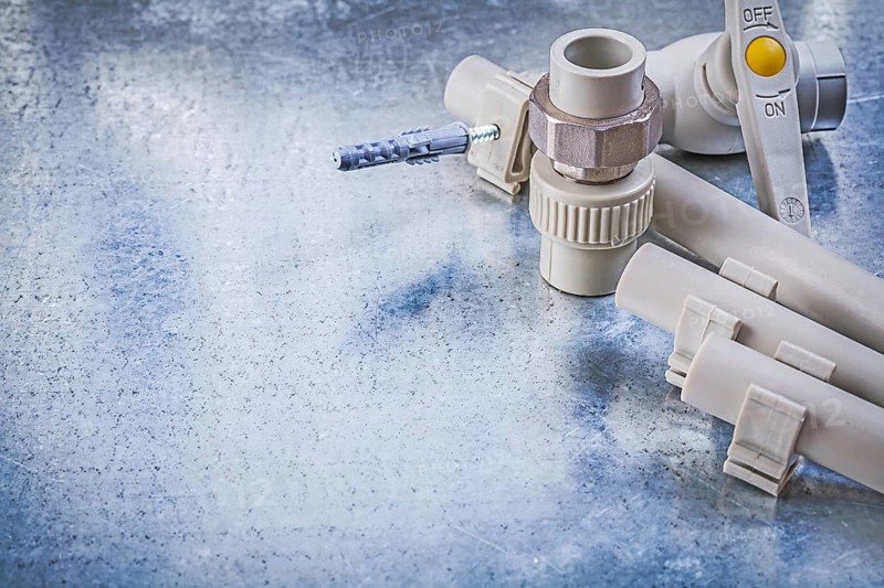 Plastic water pipe valve clamps connectors on metallic background construction concept