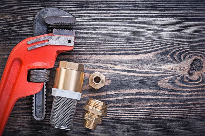 Pipe wrench check valve with strainer filter hose nipples on wooden board
