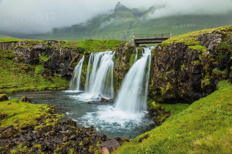 Threaded full-flowing waterfall on the grassy mountains. Iceland - country of mountains, rivers and waterfalls