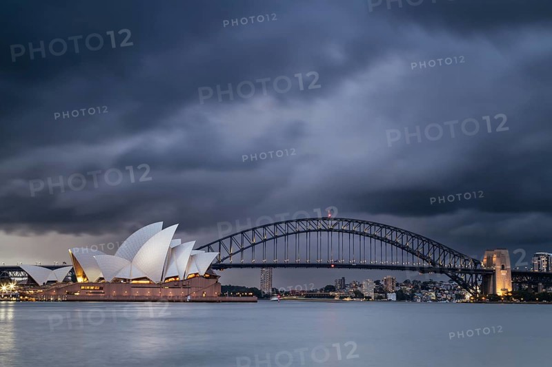 SYDNEY, AUSTRALIA, DECEMBER 03 2023: Sydney Opera House and Harbour Bridge at dusk during a summer storm from Mrs Macquarie's Chair in Sydney, New South Wales, Australia, Oceania