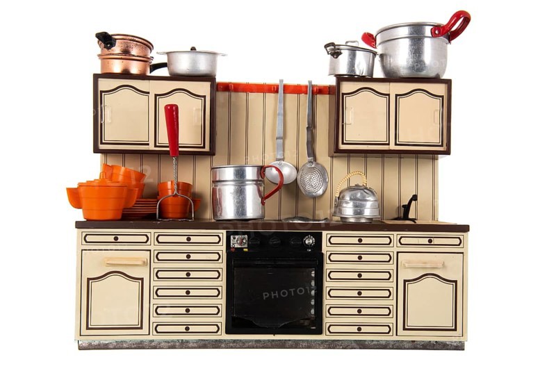 Miniature vintage toy kitchen with utensil isolated over white background