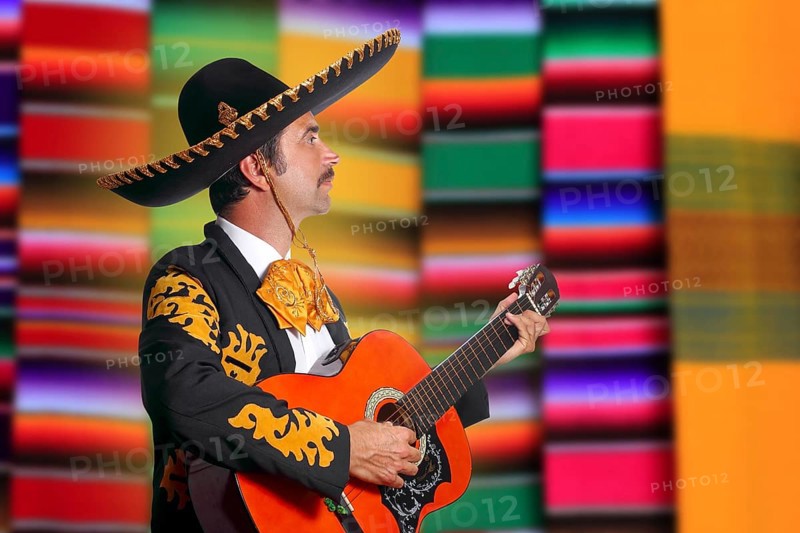 Charro Mariachi profile man playing guitar with blurred serape background