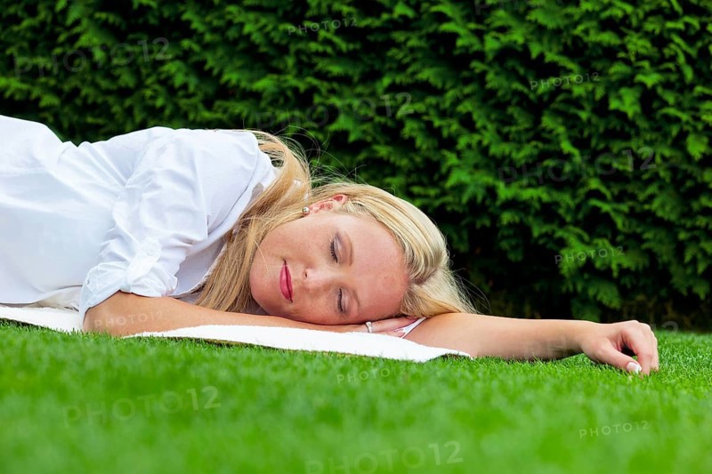 A young woman lies in the meadow to relax. Lunch break in the park. Austria