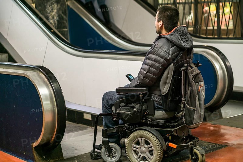 Rear View Of A Disabled Man On Wheelchair In Front Of Staircase