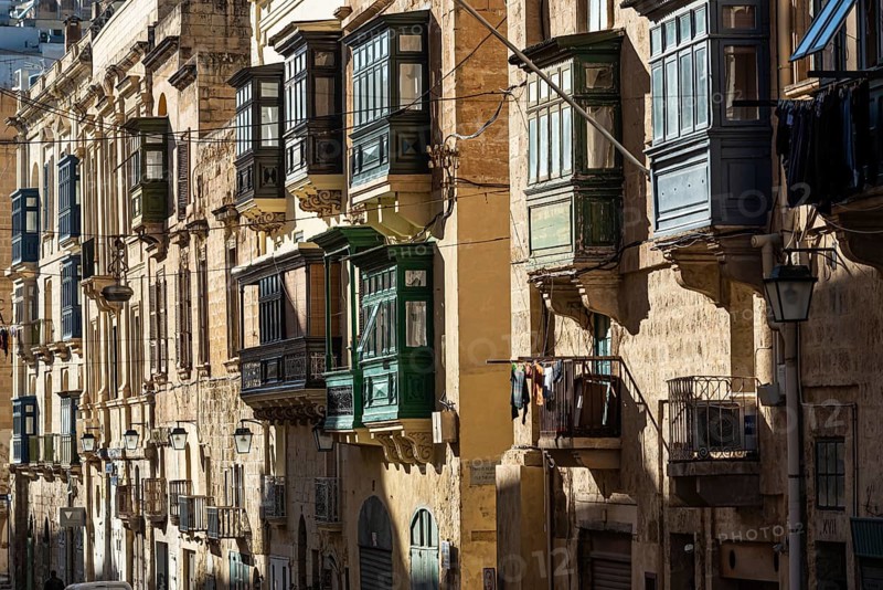 Valletta, Malta, 01 07 2022: Historical houses with wooden bow windows and terraces in a narrow street, Europe