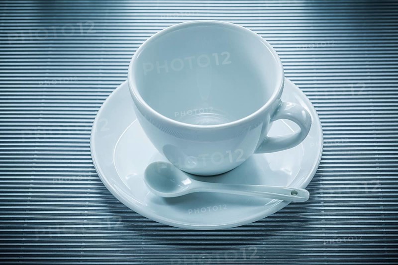 Coffee cup saucer teaspoon on striped background