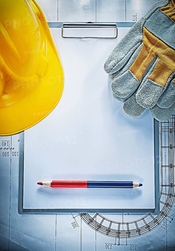 Clipboard pencil building helmet safety gloves on blueprint construction concept