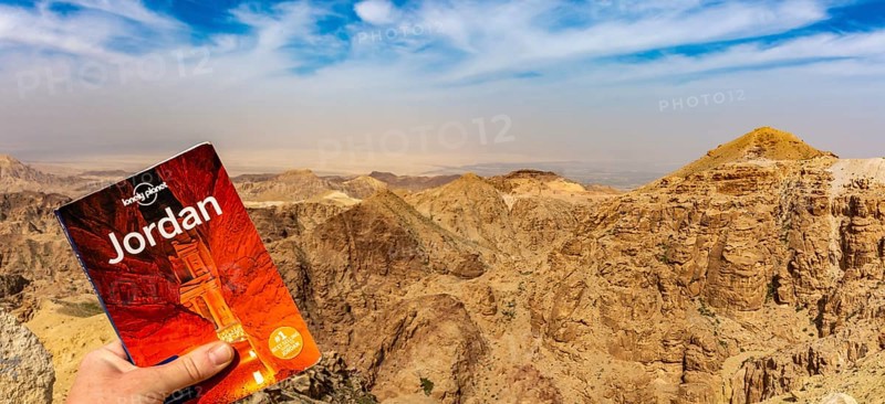 Lonely Planet travel guide against dramatic Jordan mountains and sky to promote travel and tourism to Jordan