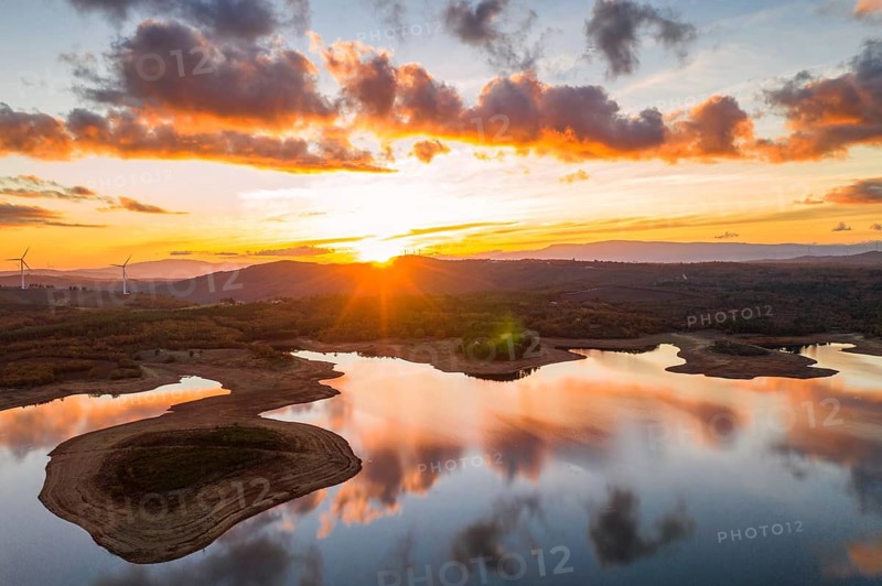 Drone aerial view of a lake reservoir of a dam with perfect reflection on the water of the sunset in Sabugal, Portugal, Europe