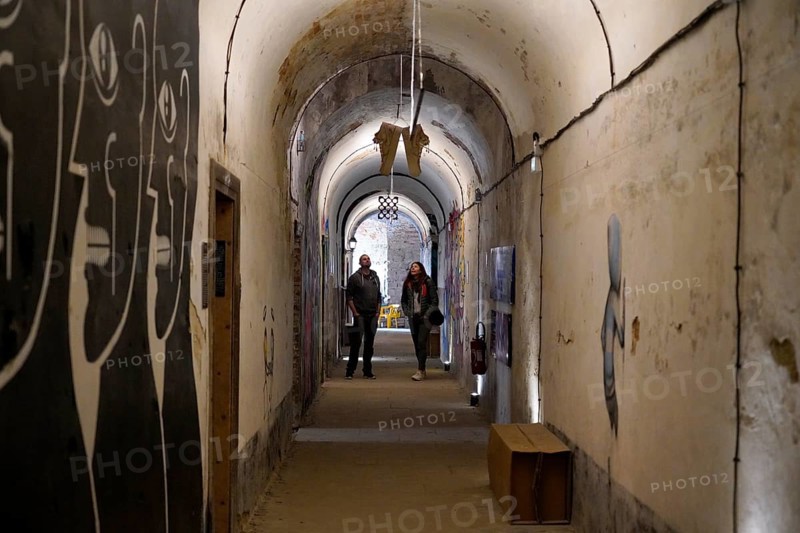 MAUSA VAUBAN, Museum of Urban Art and Street Art, Neuf-Brisach Fortress, France, Europe, Long underground corridor with gloomy wall art and two people in the background, Europe