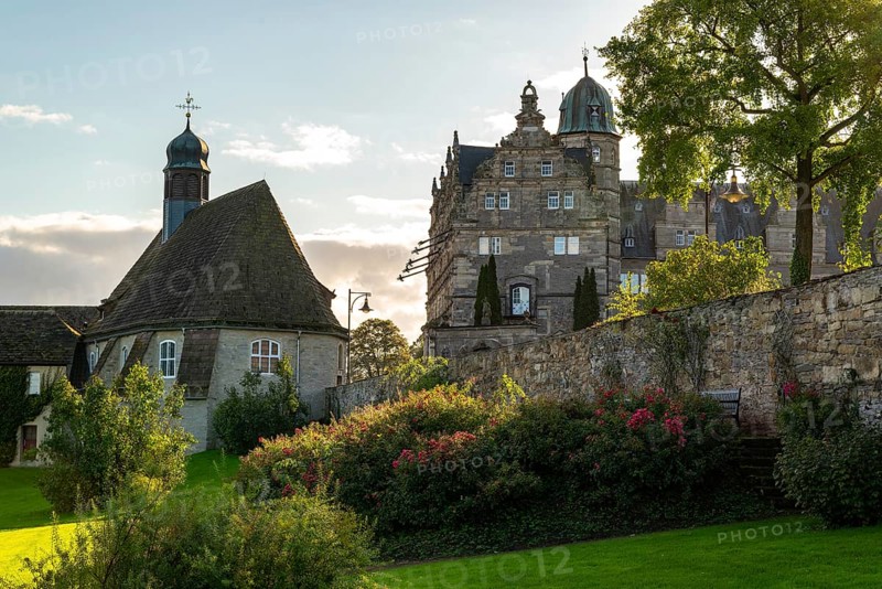 Historic Hämelschenburg Castle with castle church, well-tended garden and old walls in the evening light, Weserbergland, Lower Saxony, Germany, Europe