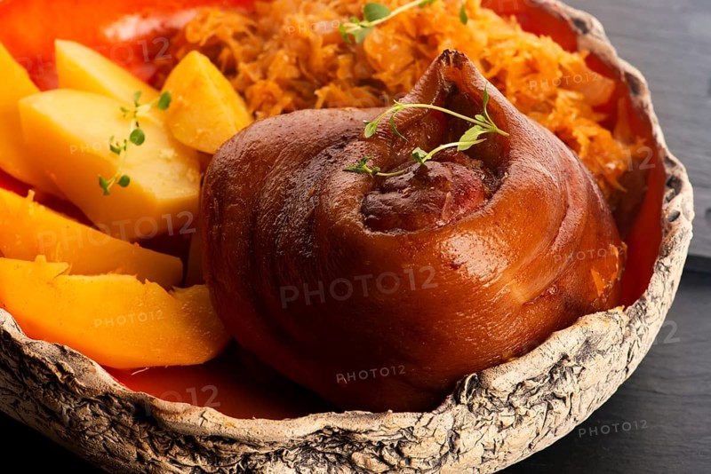 Appetizing baked pork knuckle with potatoes and cabbage on plate