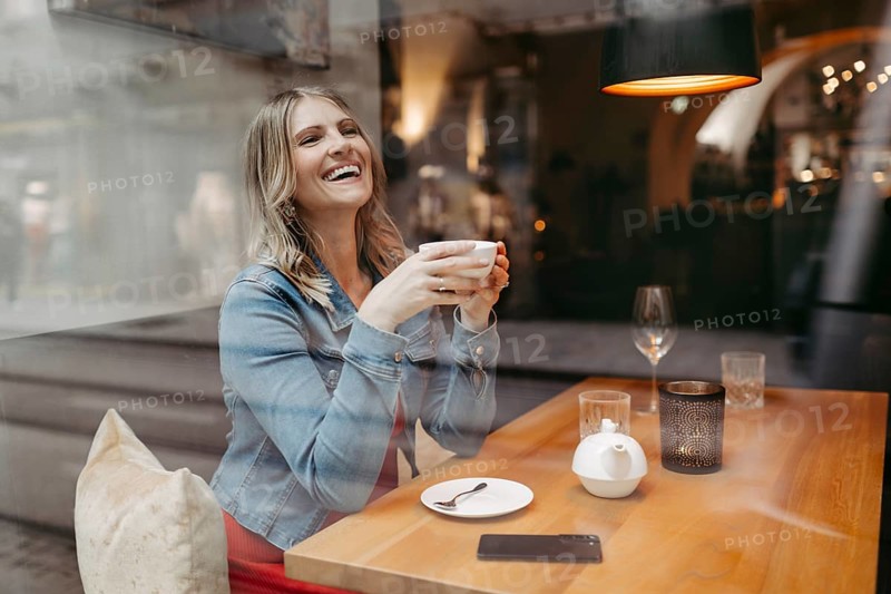 Blonde, attractive woman, 40+, sitting in a coffee house by the window