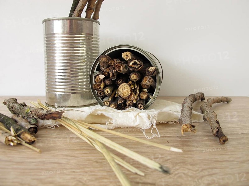 Homemade insect hotel made from tins, sticks and straw