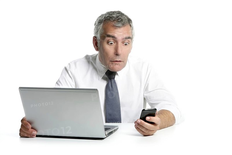 Surprised senior businessman expression gesture mobile phone laptop gray hair