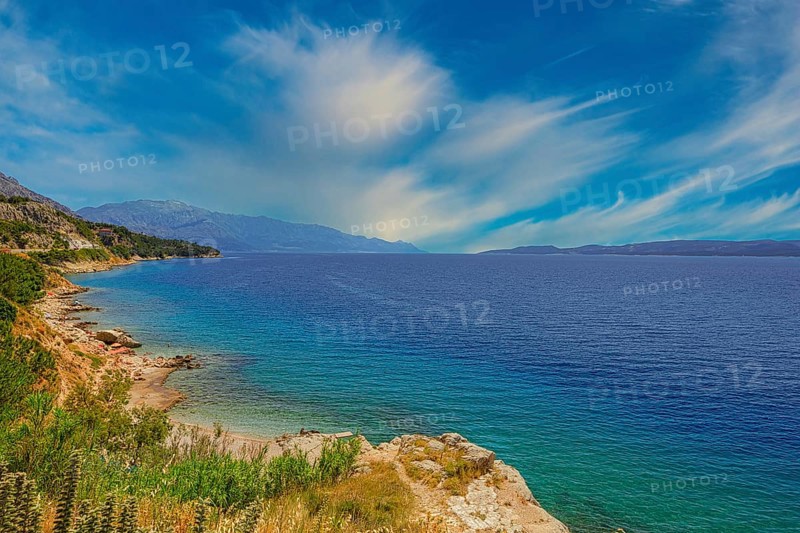Coastal landscape with blue sea and green shore, peaceful sky with cloud patches, Makarska coast Dalmatia Croatia