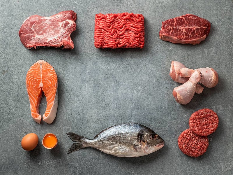 Carnivore or keto diet concept. Raw ingredients for zero carb or low carb diet - meat, poultry, fish, eggs and copy space in center on gray stone background. Top view or flat lay