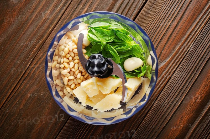 Ingredients for italian national traditional genovese pesto sauce in food processor bowl. Flat lay view
