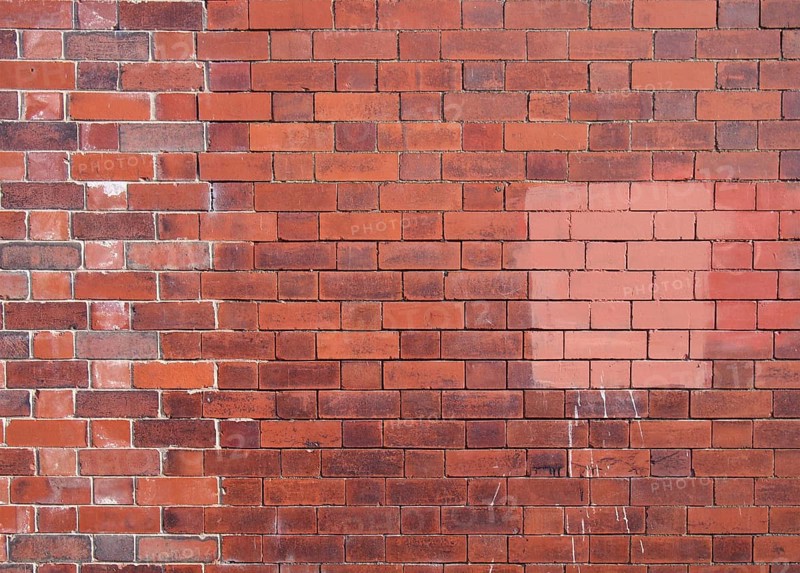An old repaired patched exterior wall made of red bricks