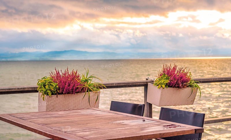 Conceptual image with an empty table, on a terrace, on the shore of the Bodensee lake, at sunset