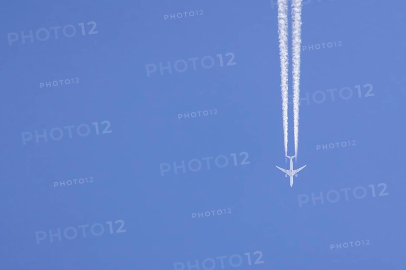 Airbus aircraft of Qatar airways flying across a blue sky with a vapour trail or contrail behind, England, United Kingdom, Europe
