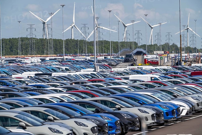 Storage area for new cars in the port of Vlissingen-Oost, vehicles are temporarily stored on over 100 hectares to ship them from Europe to the United Kingdom, Ford cars, others such as models from the Chinese car manufacturer BYD are delivered from here in Europe, wind farm, Netherlands