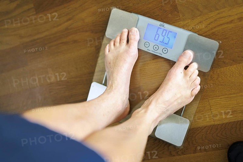 Symbolic photo on the subject of body weight. The feet of a 60-year-old person can be seen next to the weight display of a scale. Berlin, 13.08.2024