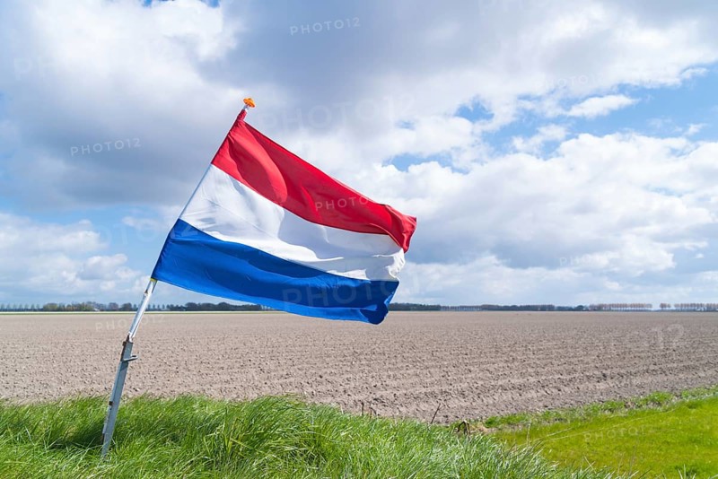 Waving dutch flag in a typical flat agricultural landscape