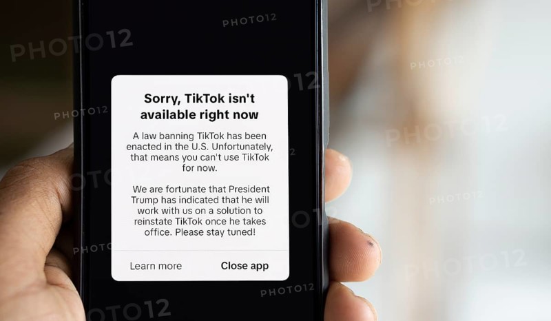 An iPhone screen with the TikTok homepage showing Sorry, TikTok isn't available right now