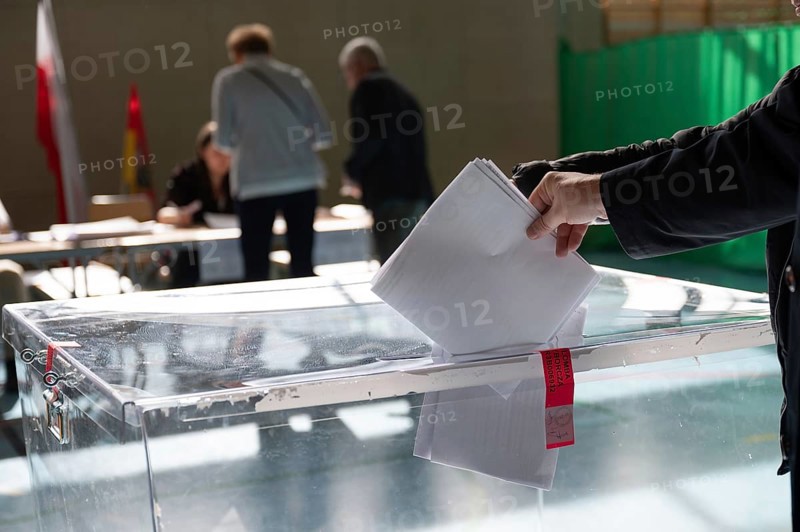 Voter's hand putting the vote into the ballot box.