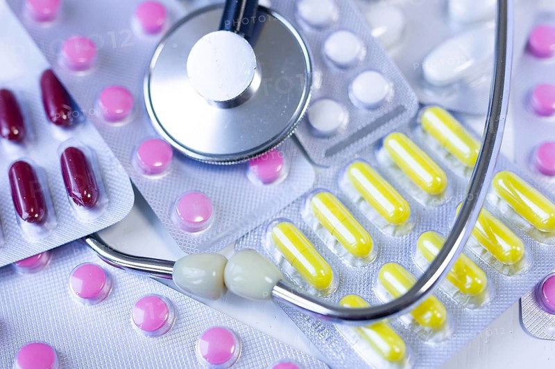 Blister packs with colorful pills alongside a stethoscope