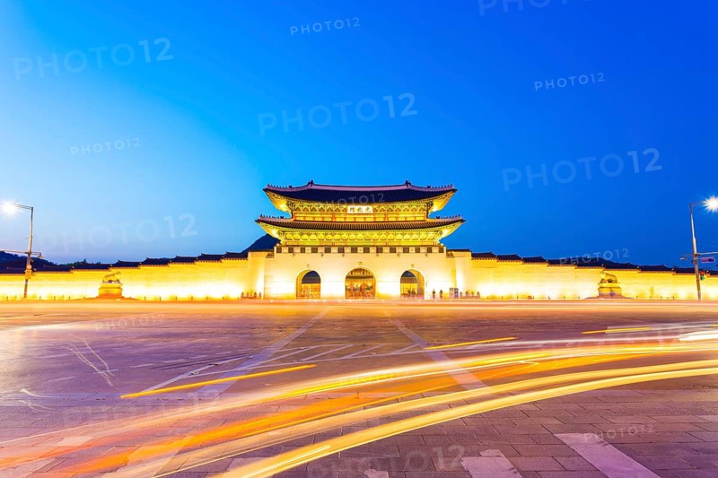 Long exposure car lights curving in front of Gwanghwamun main entrance gate to Gyeongbokgung Palace in historic part of downtown Seoul, South Korea on a clear, dusk night