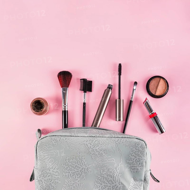 Makeup products spilling out bag pink background