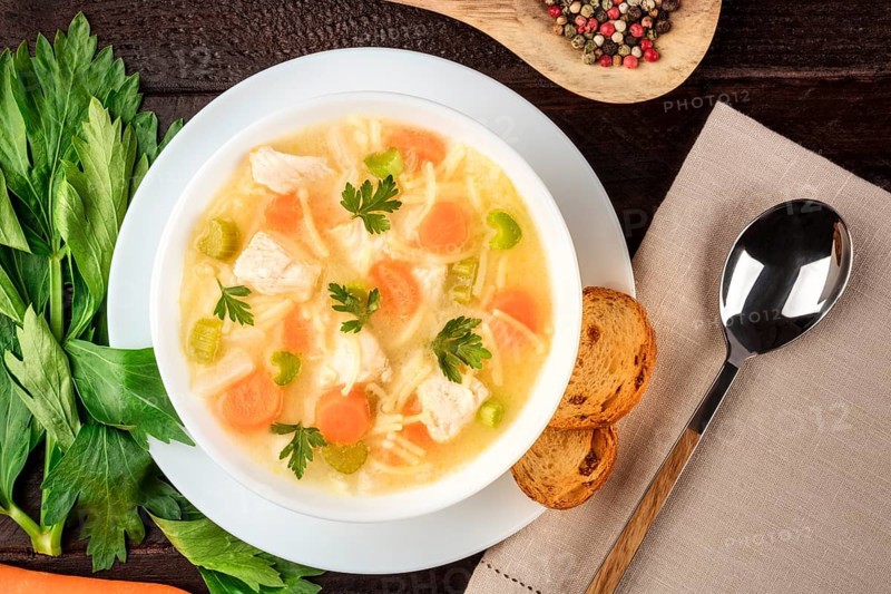 Chicken noodle soup, shot from the top on a dark rustic wooden background with a place for text