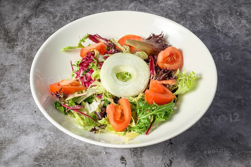 Green vegan salad from green leaves mix and vegetables. Top view on gray stone table