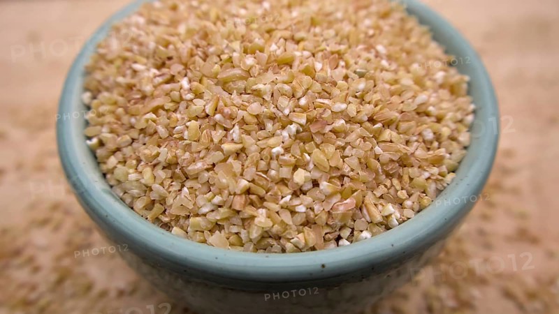 Broken Crushed Wheat (Dalia) in a Blue Bowl Isolated on Wooden Background, Close up