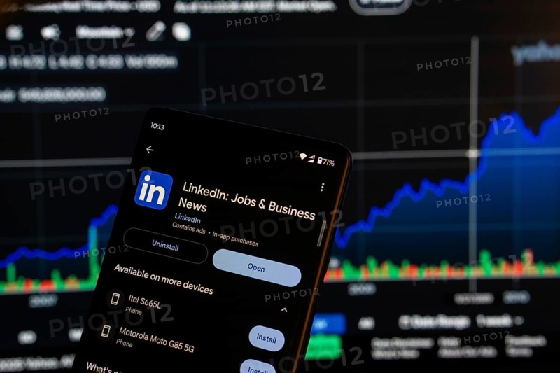 Dhaka, Bangladesh 08 March 2025: Linkedin jobs and business app installation screen on a smartphone and the financial market chart in the background